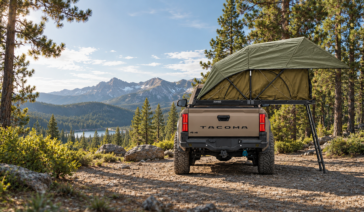 Toyota Tacoma with a bed-mounted rooftop tent camped in the mountains