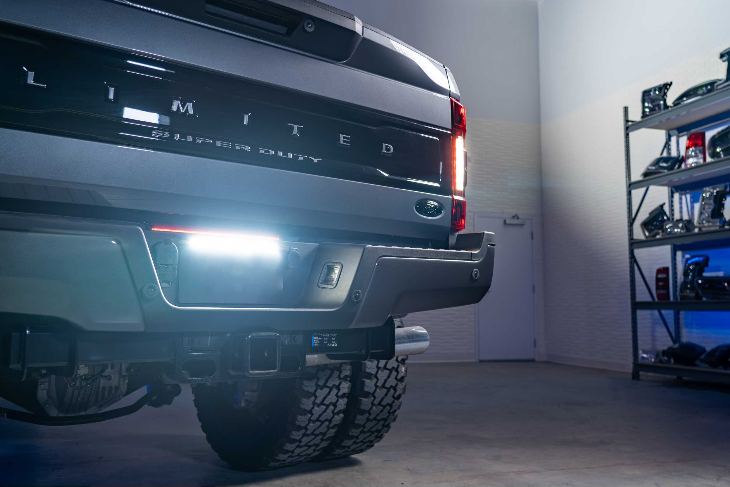 Rear view of a Ford Super Duty truck with illuminated LED reverse lights in a garage.