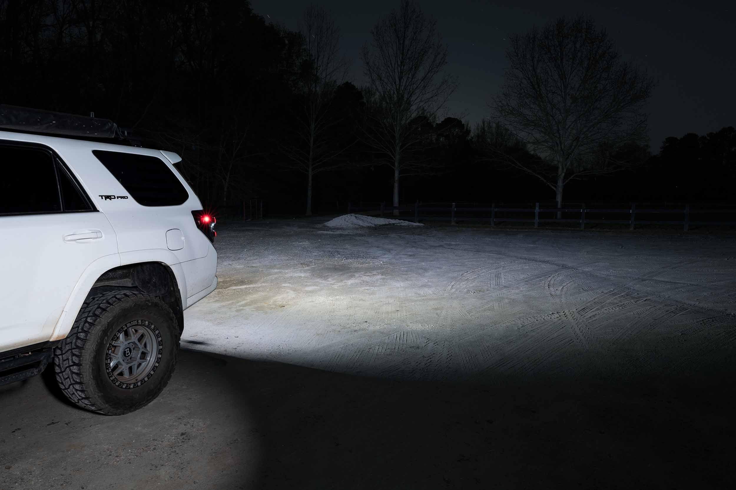 Toyota 4Runner TRD Pro SUV with off-road tires illuminating a dirt area at night