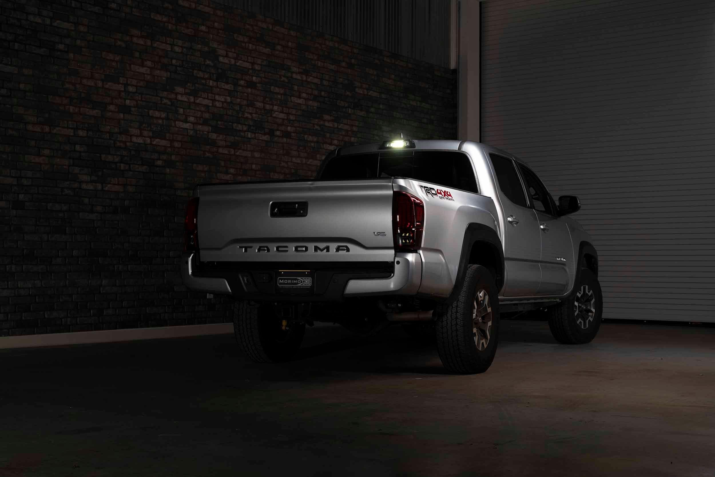 Silver Toyota Tacoma TRD Off Road pickup truck with aftermarket lighting, parked indoors