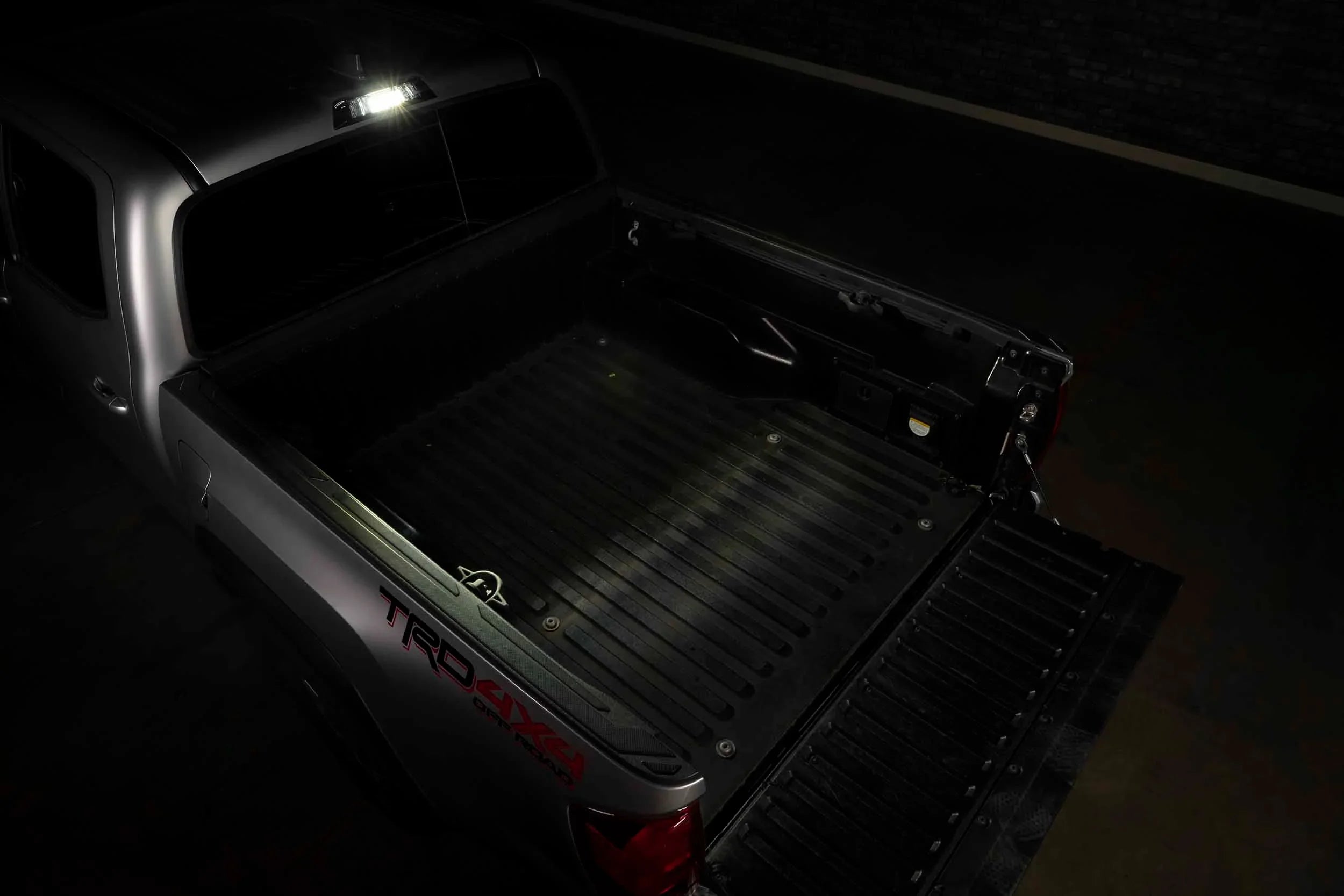 Toyota Tacoma TRD 4x4 open truck bed at night with cargo area lighting