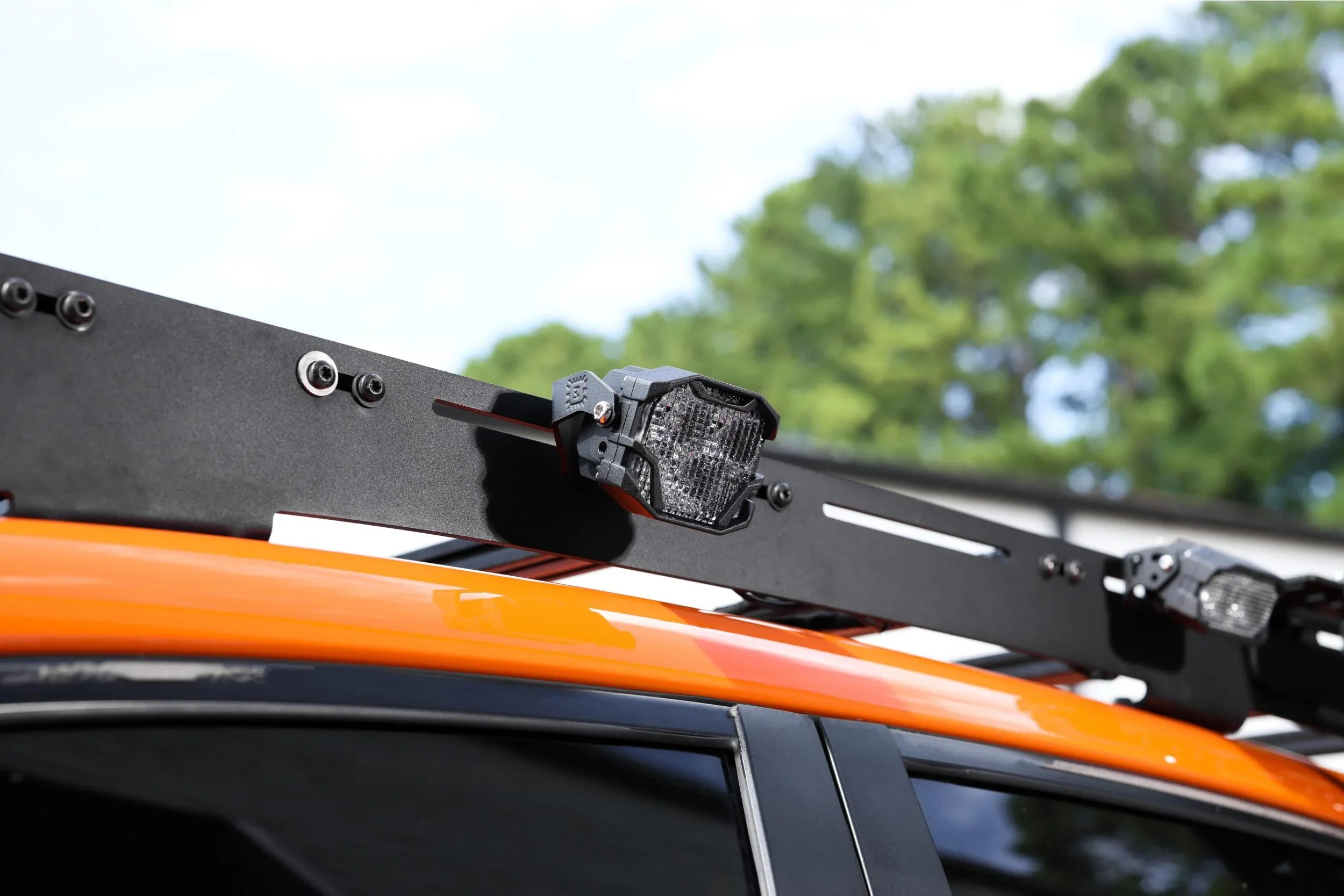 Black modular roof rack with mounted LED lights on orange off-road vehicle