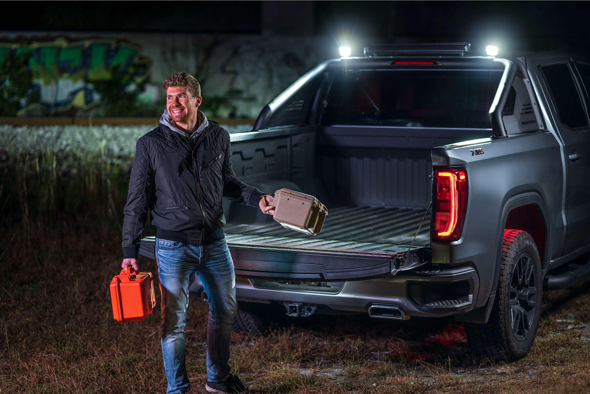 Man holding gear cases by pickup truck with overlanding accessories at night