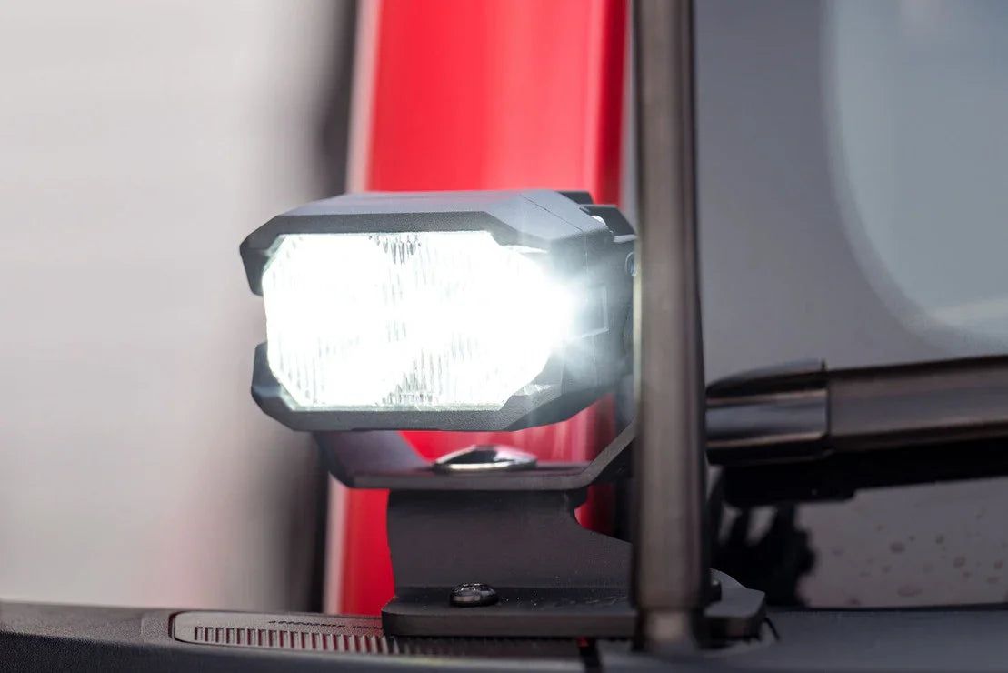 Close-up of a bright LED off-road light mounted on a vehicle windshield pillar