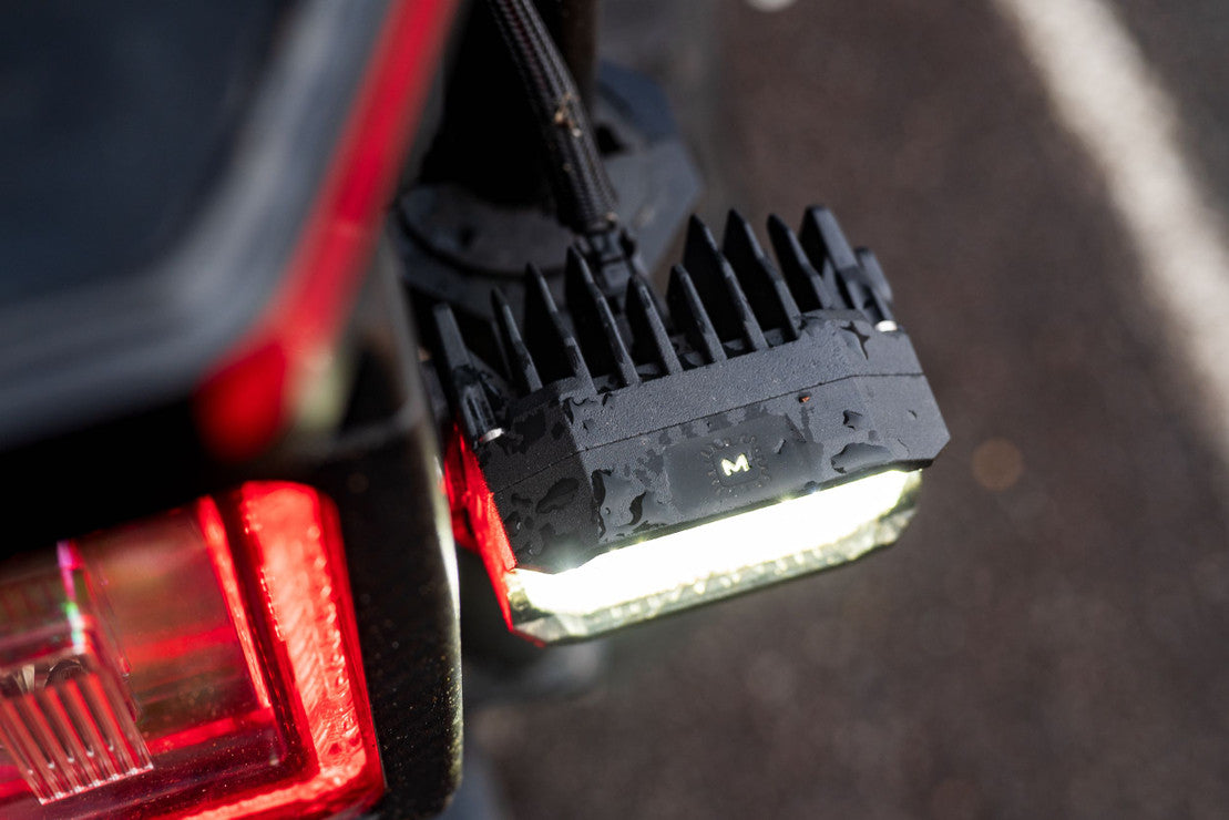 Close-up of an LED off-road pod light mounted on a vehicle with visible water droplets