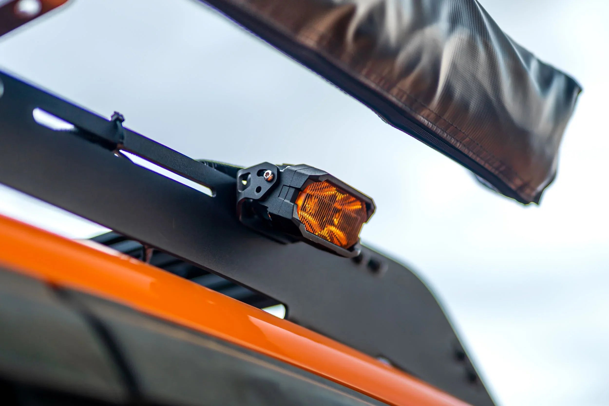 Amber off-road LED light mounted on a vehicle roof rack, ideal for overlanding gear
