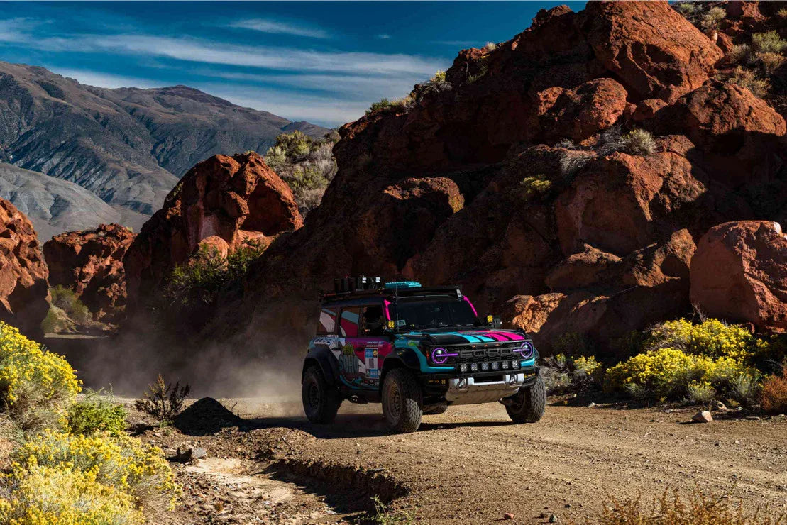 Off-road Ford Bronco with custom graphics driving through rocky desert trail