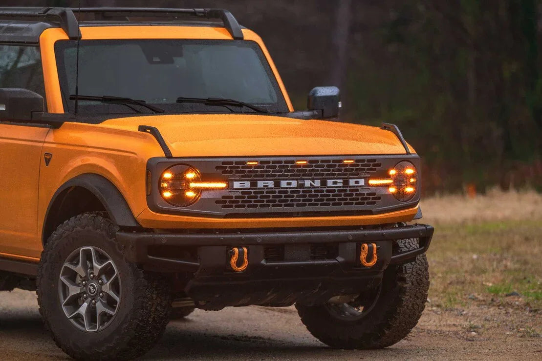 Orange Ford Bronco off-road SUV with rugged tires and front tow hooks, parked outdoors