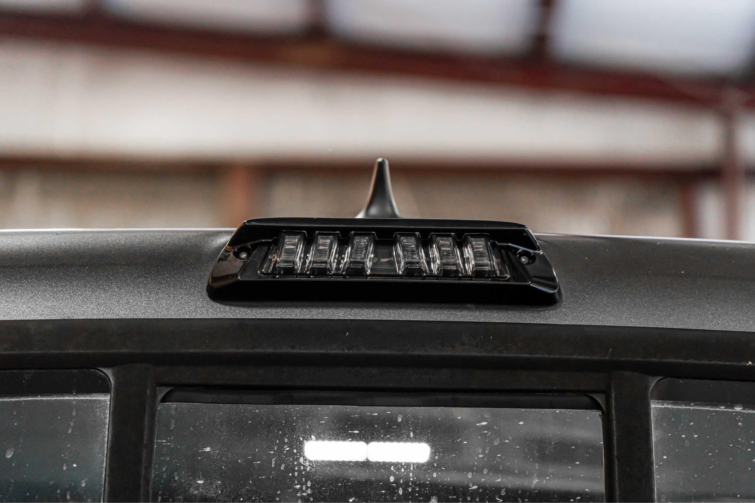 Aftermarket LED third brake light installed on a truck cab roof, close-up view.