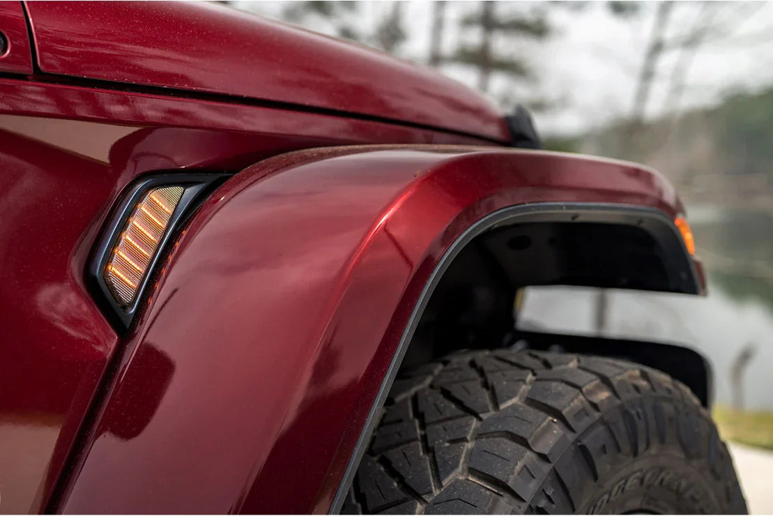 Close-up of a red Jeep Wrangler fender with amber side marker light and off-road tire