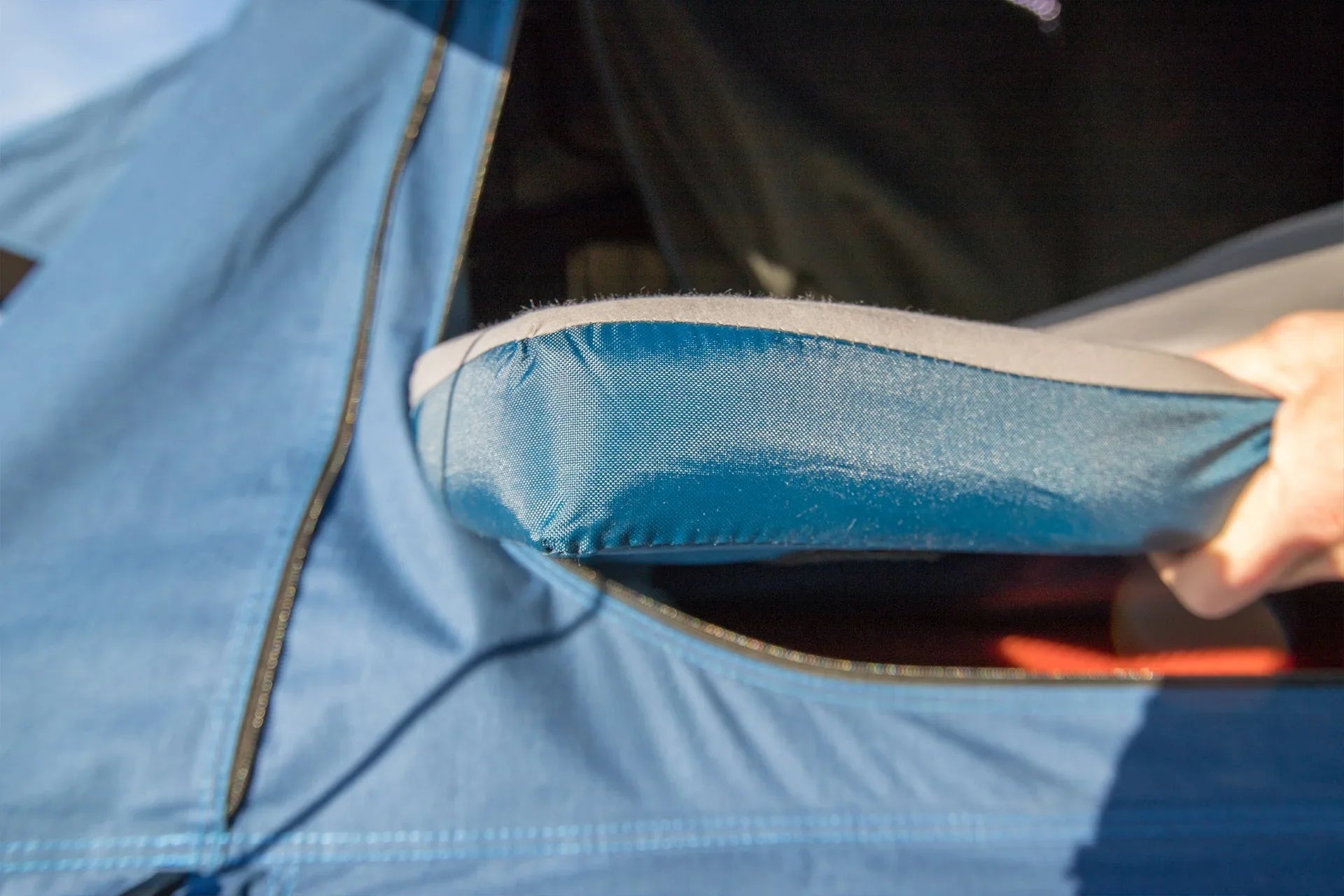 Close-up of a padded handle on a blue overlanding roof top tent with zippered opening