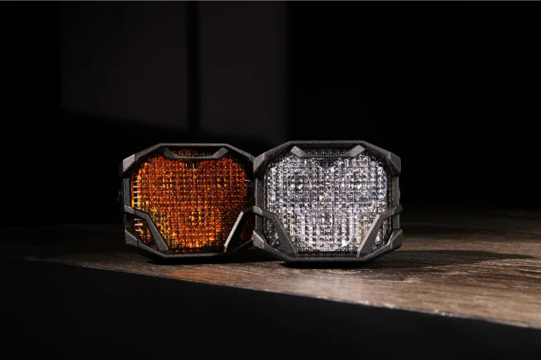Amber and white LED pod lights for off-road vehicles on a wooden surface