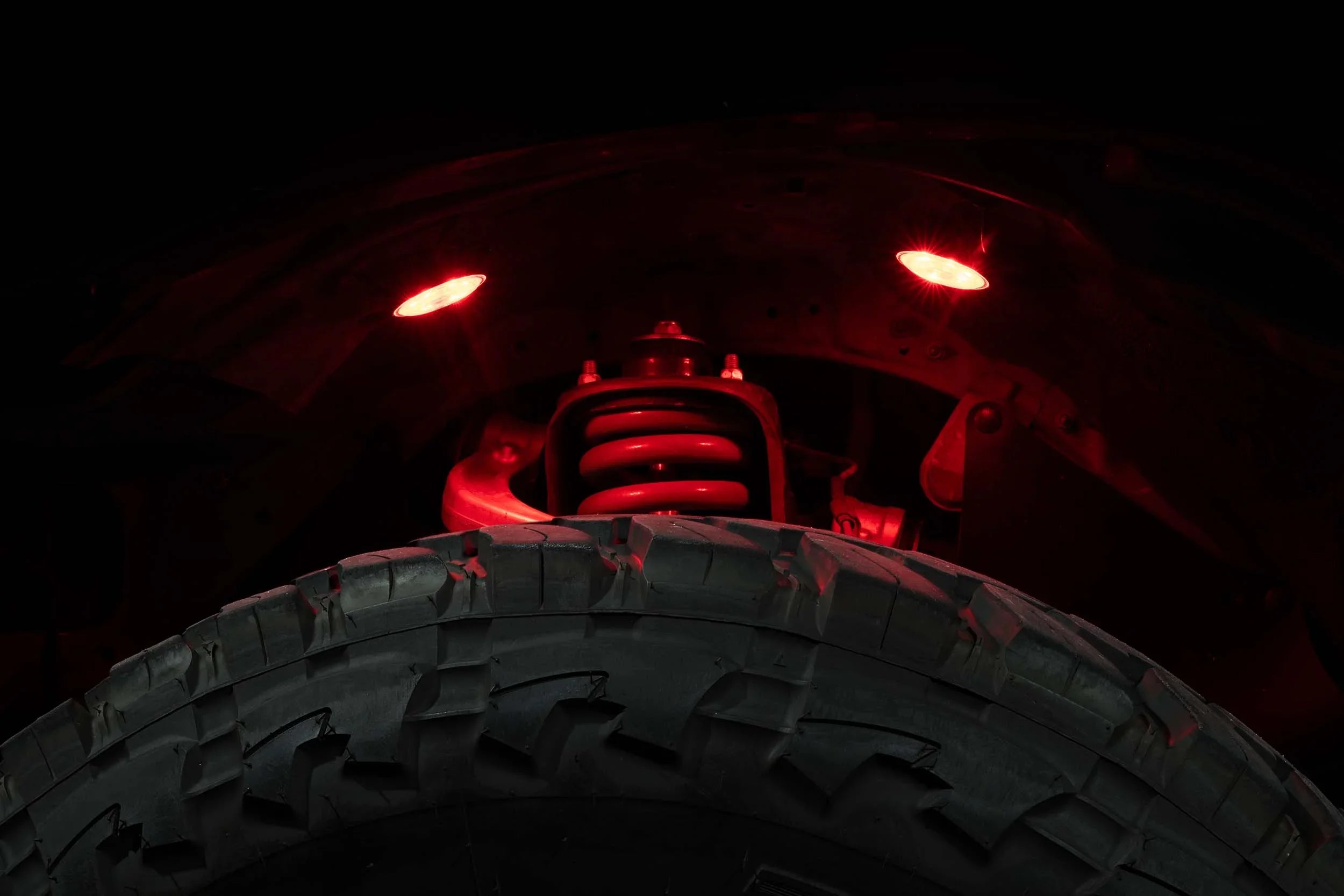 Off-road tire with illuminated red suspension and fender lights for trucks or SUVs