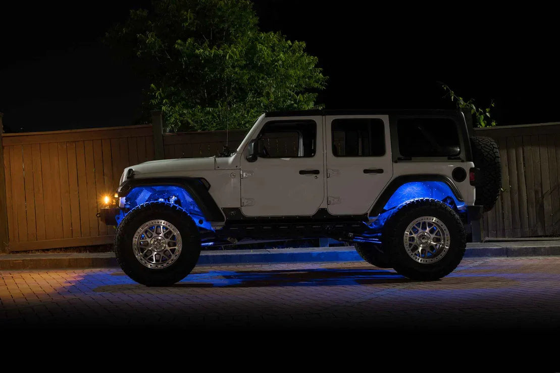 Jeep Wrangler with off-road wheels and blue underglow lights parked at night