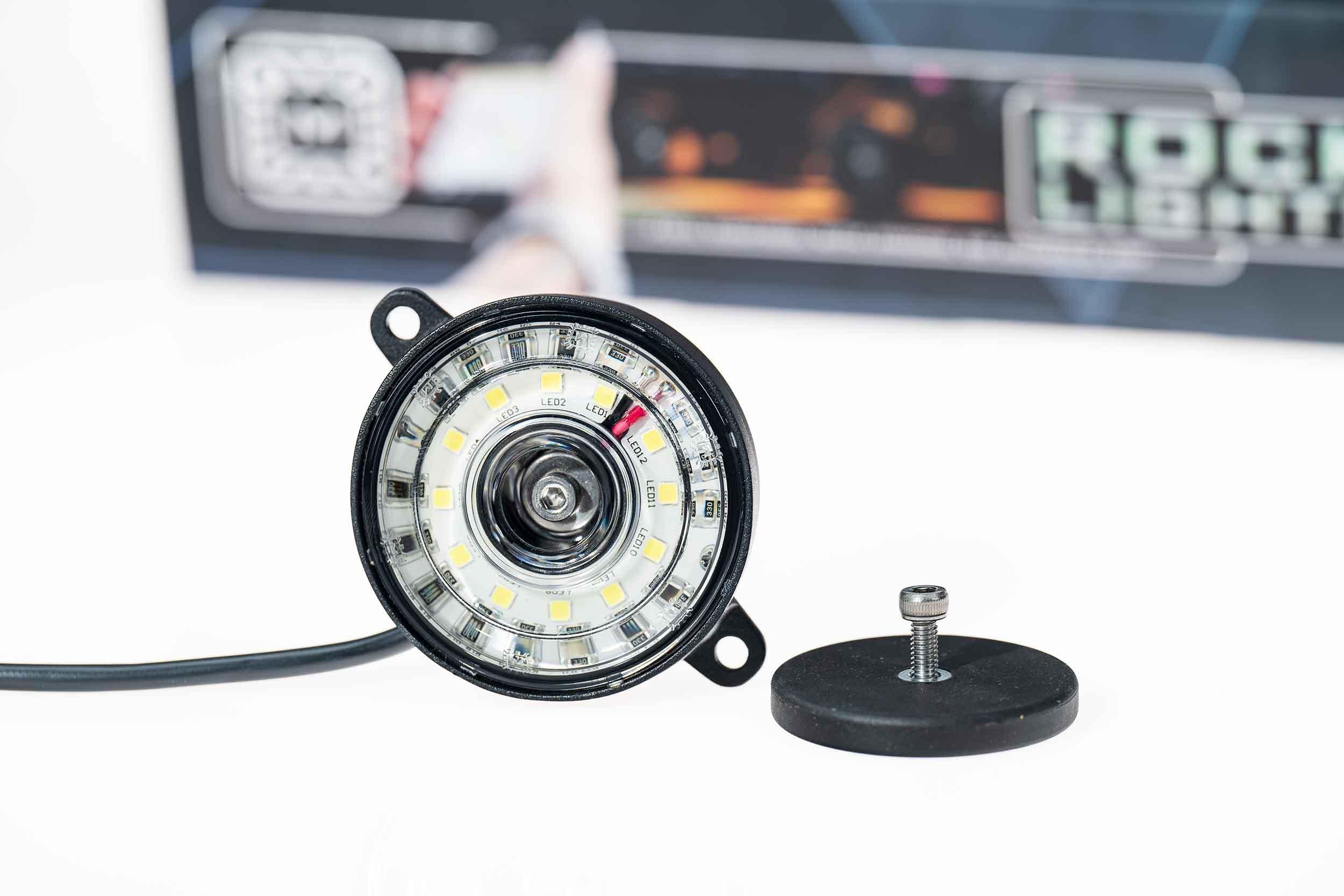 Close-up of round LED rock light with mounting hardware for off-road vehicle lighting