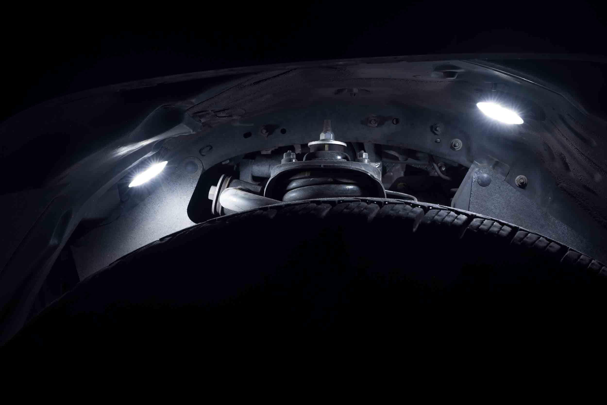 Vehicle wheel well LED rock lights illuminating suspension and tire at night