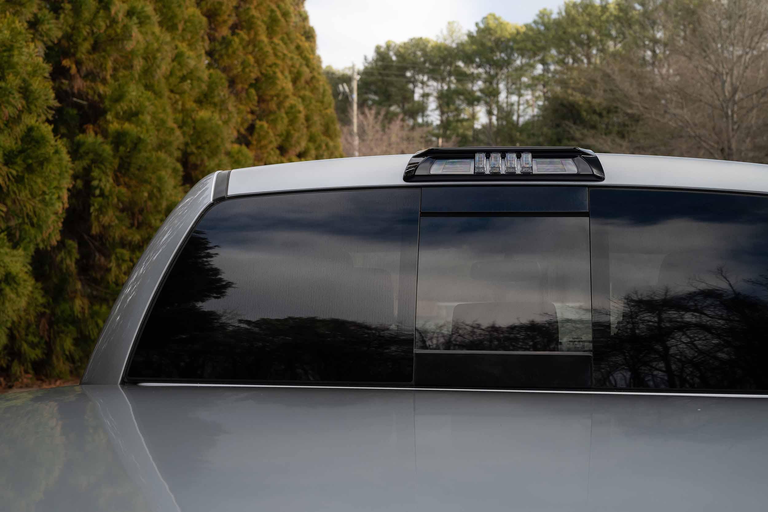 Toyota Tacoma rear window with aftermarket LED third brake light under trees