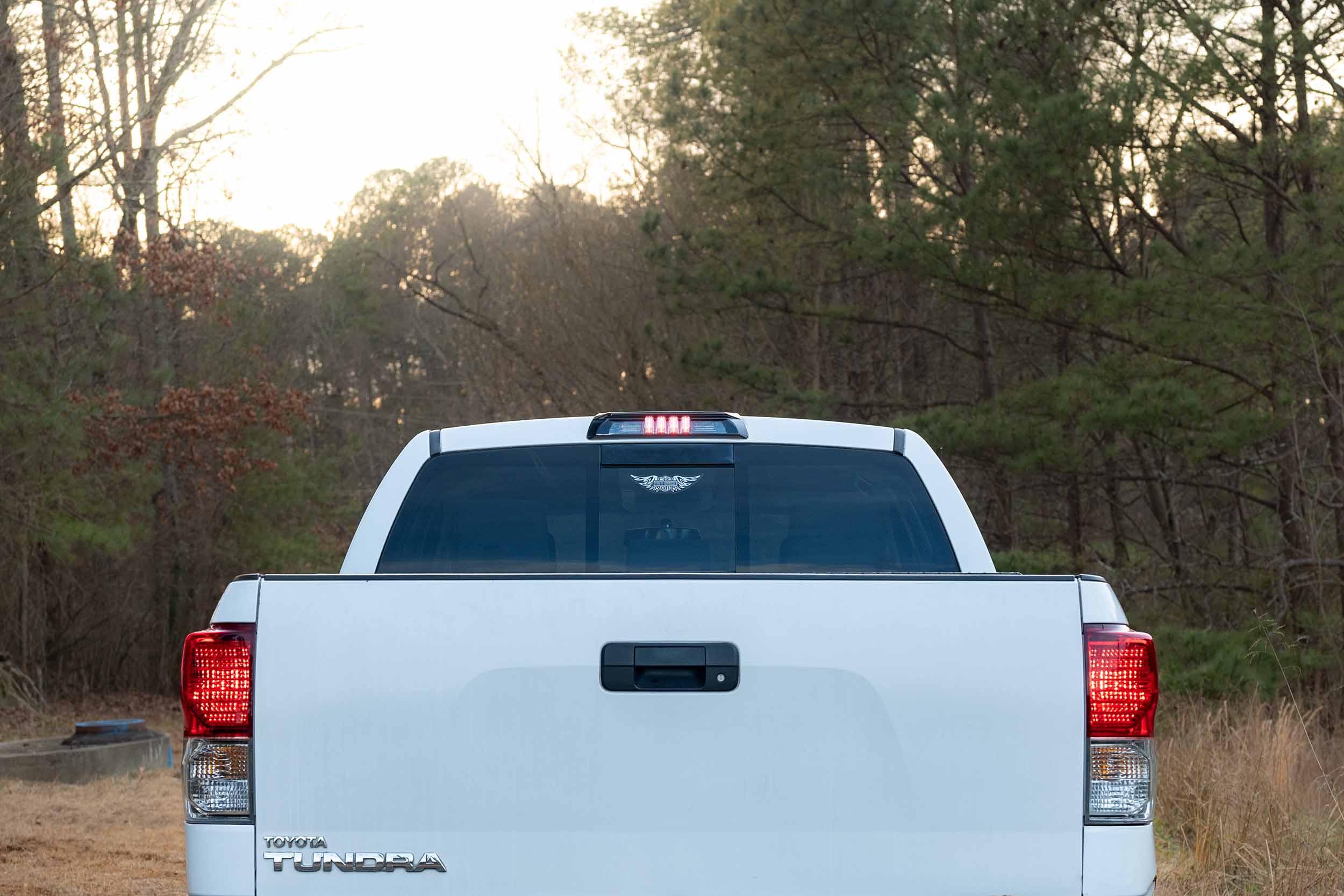 Rear view of a white Toyota Tundra pickup truck in a wooded outdoor setting