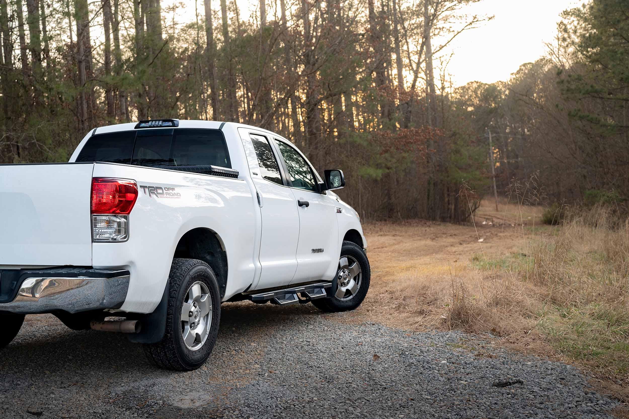 White Toyota Tundra TRD Off-Road pickup truck parked at forest trail entrance
