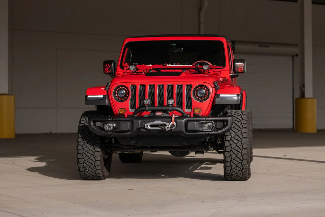 Red Jeep Wrangler Rubicon with off-road mods, LED halo headlights, and rugged tires