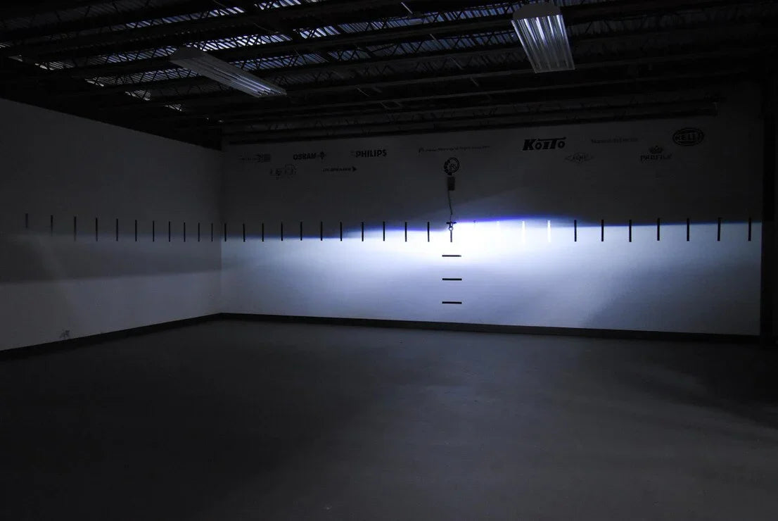 LED headlight beam pattern test on a wall in a dark indoor garage