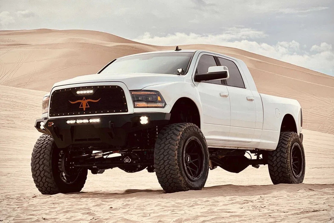 Lifted white Ram truck with off-road tires and amber XB LED headlights in a desert setting