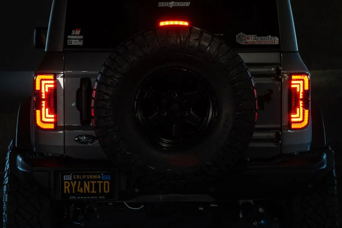 Rear view of Ford Bronco with custom LED tail lights, spare tire, and off-road accessories.