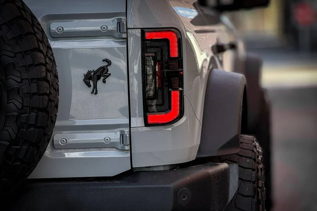 Close-up of Ford Bronco rear with rugged tire and LED tail light, off-road vehicle accessory