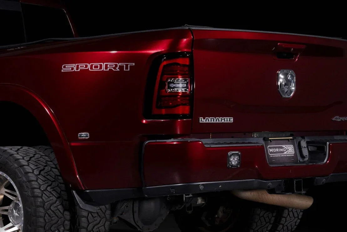 Close-up of red Ram pickup truck rear with Sport and Laramie badges, off-road tires, LED tail lights.