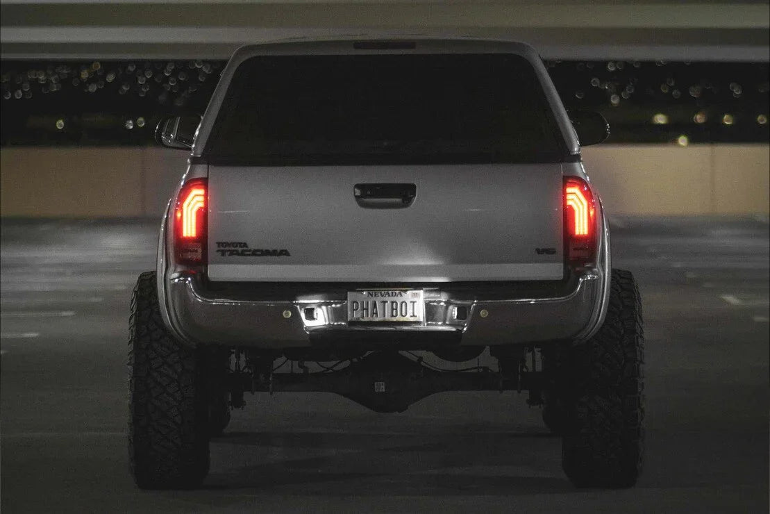 Lifted Toyota Tacoma V6 truck rear view in parking garage, aftermarket tail lights, off-road tires