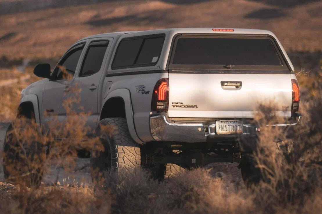 Toyota Tacoma TRD Sport off-road truck with camper shell in a desert landscape