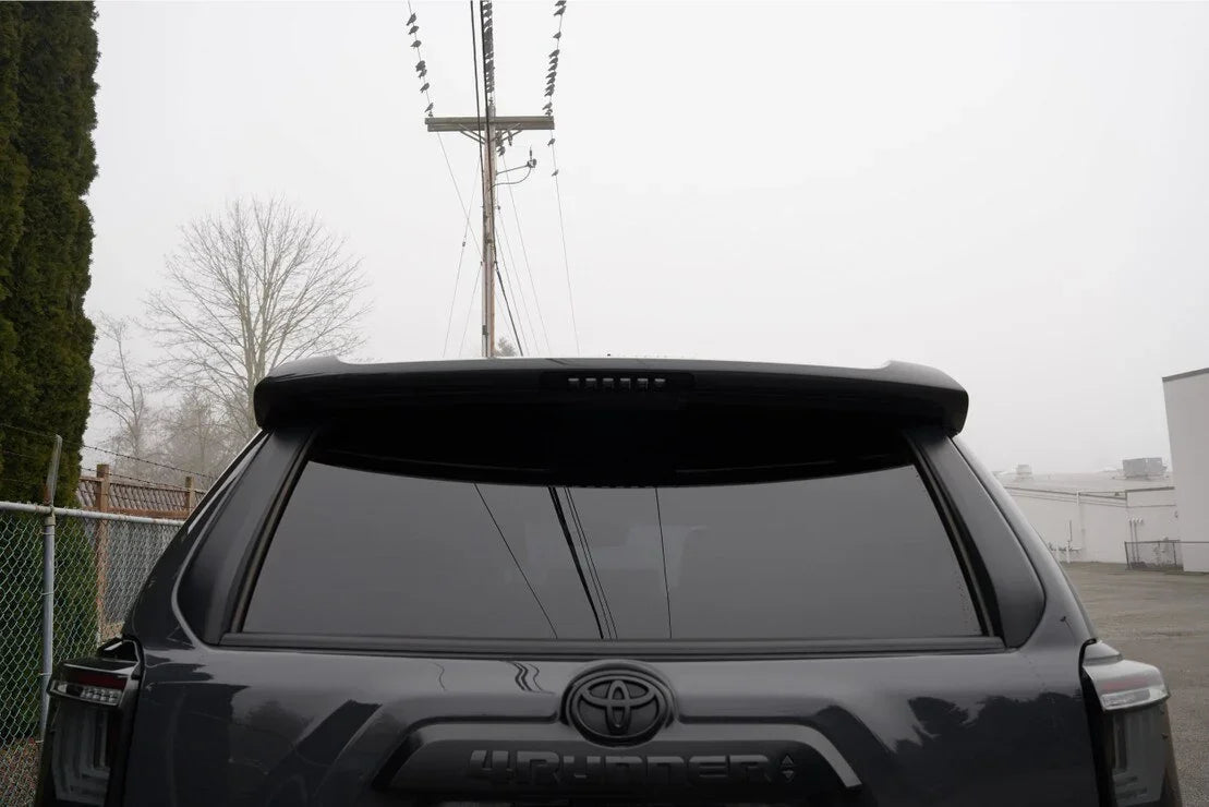 Rear view of a Toyota 4Runner SUV with tinted windows and rear spoiler in an outdoor setting