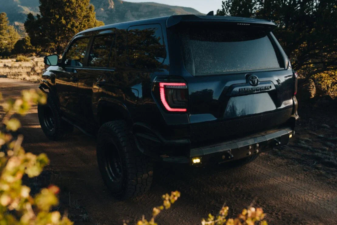Toyota 4Runner SUV with off-road tires parked on a dirt trail in a scenic outdoor setting