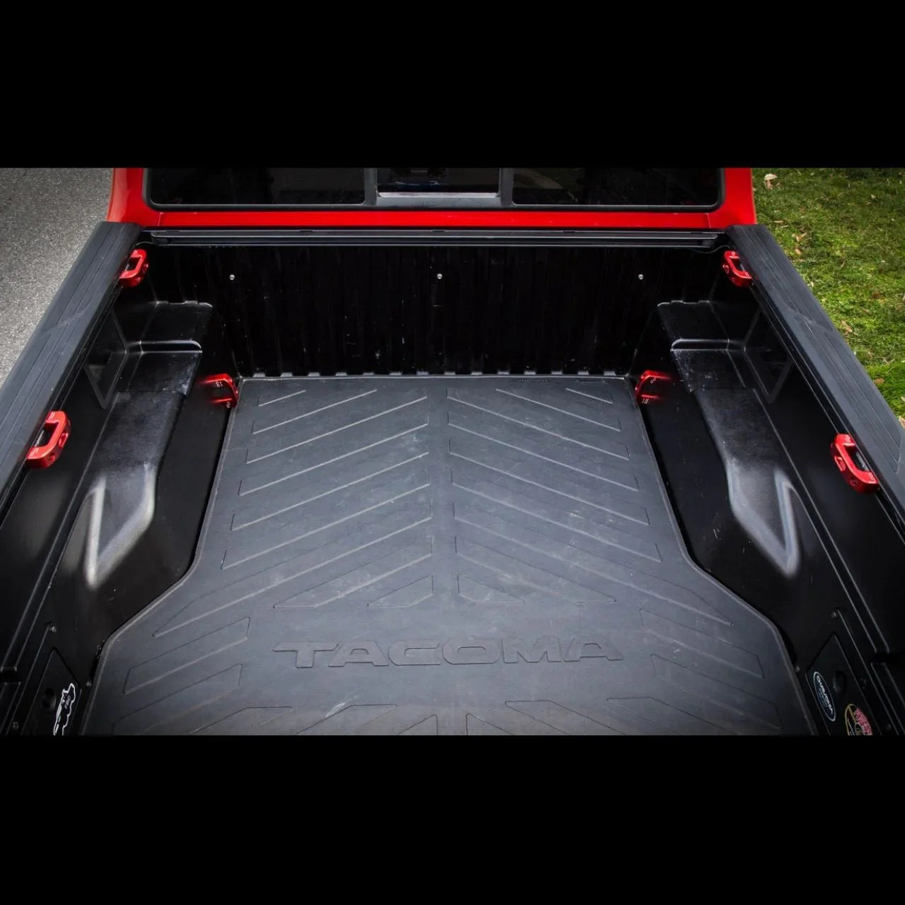 Toyota Tacoma truck bed with heavy-duty black bed liner and red tie-down hooks