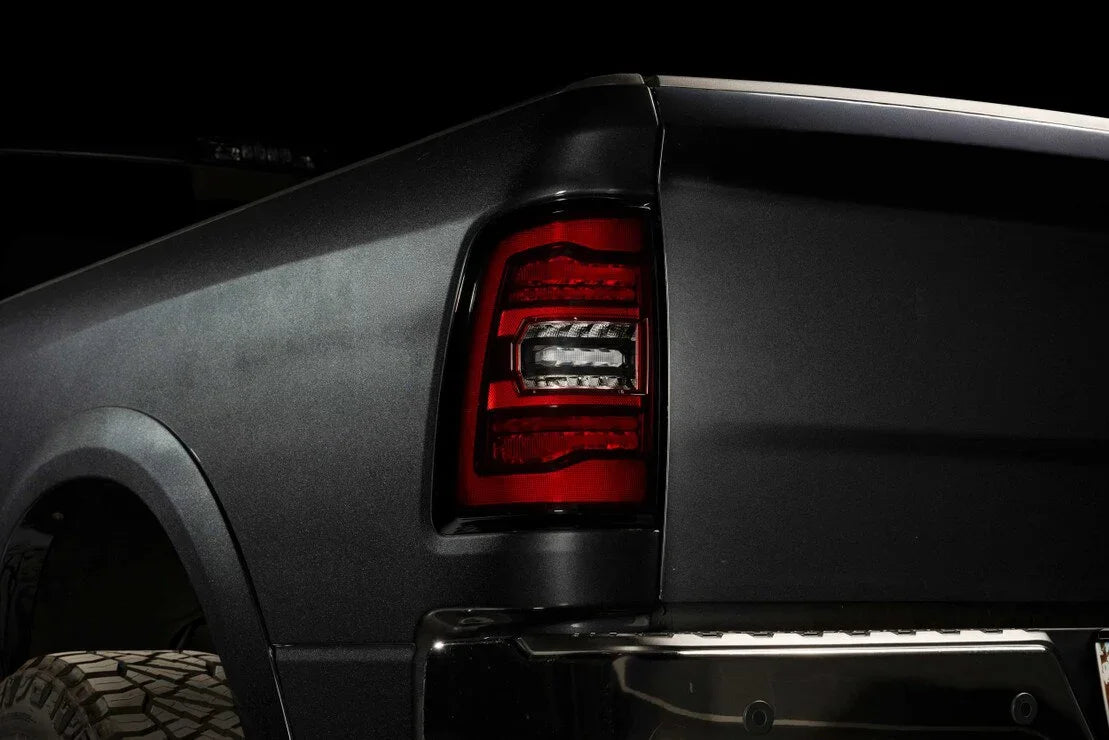 Close-up of a black pickup truck's rear tail light and fender in low light