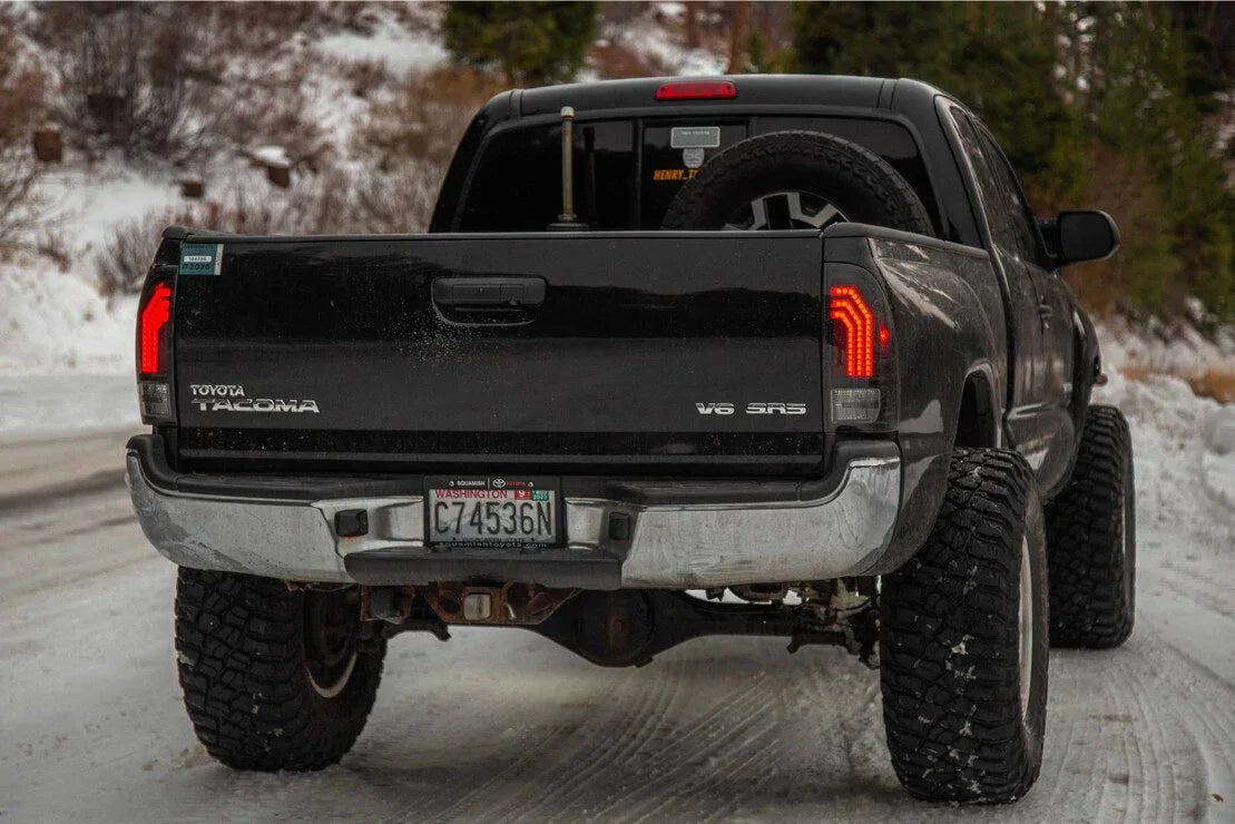 Toyota Tacoma with aftermarket clear tail lights on a snowy off-road trail