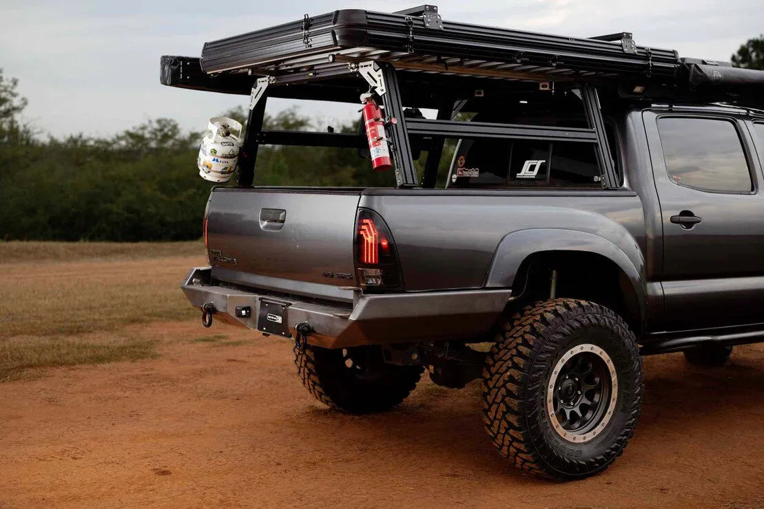 Toyota Tacoma with overlanding gear, off-road tires, roof rack, gas tank, and fire extinguisher