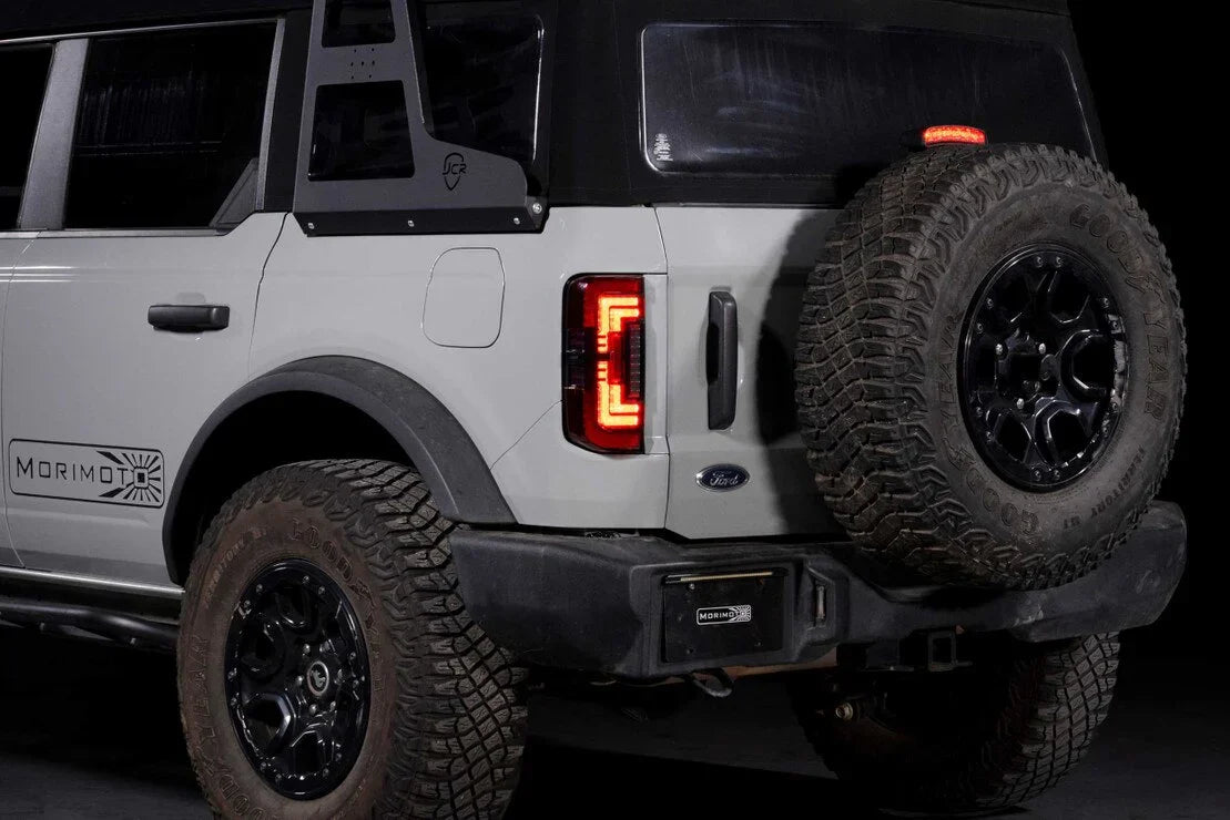Ford Bronco rear with red smoked LED tail lights, off-road tires, and spare tire mount