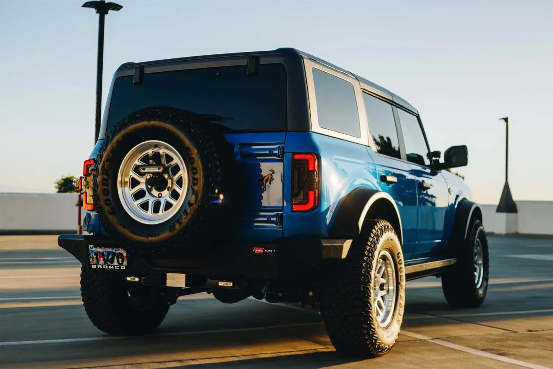 Blue Ford Bronco with aftermarket smoked red tail lights, parked outdoors, rear angle view.