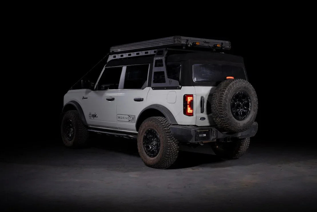 Ford Bronco with red smoked tail lights, off-road tires, roof rack, and spare tire in studio