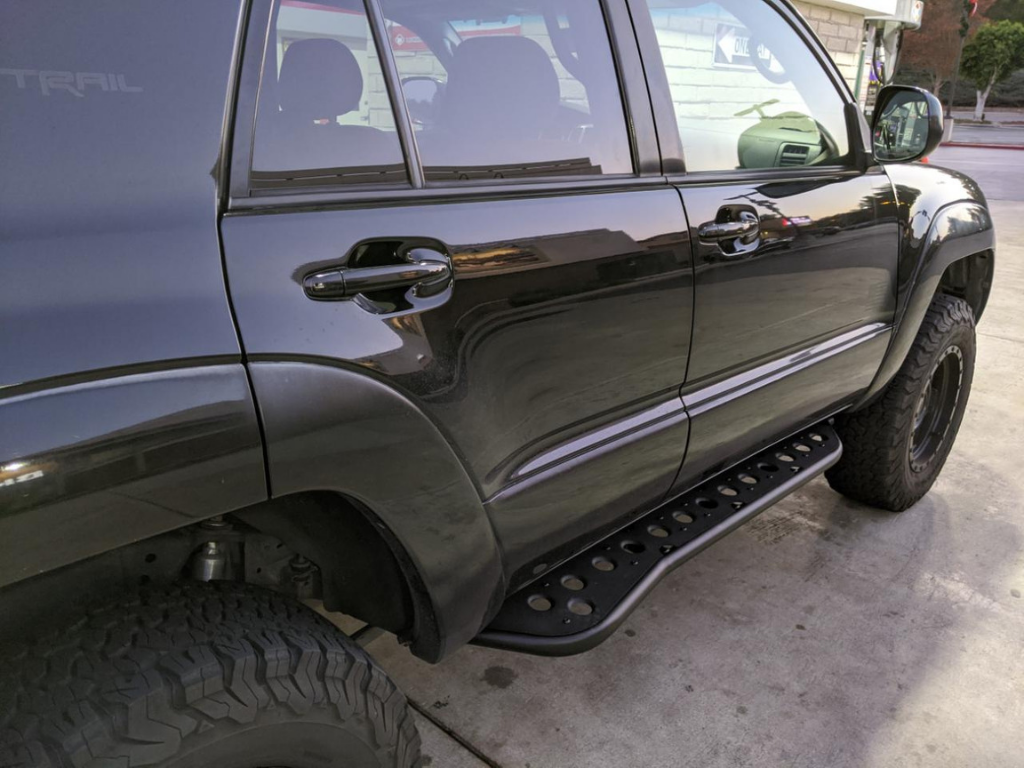 Black Toyota SUV with off-road rock sliders, large all-terrain tires at gas station