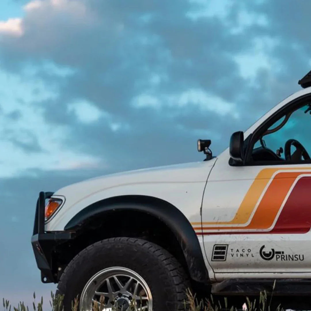 Toyota Tacoma with ditch light brackets and retro side decals parked outdoors