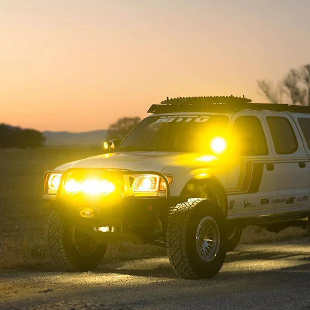 First-generation Toyota Tacoma with ditch lights and yellow off-road LED lighting at sunset