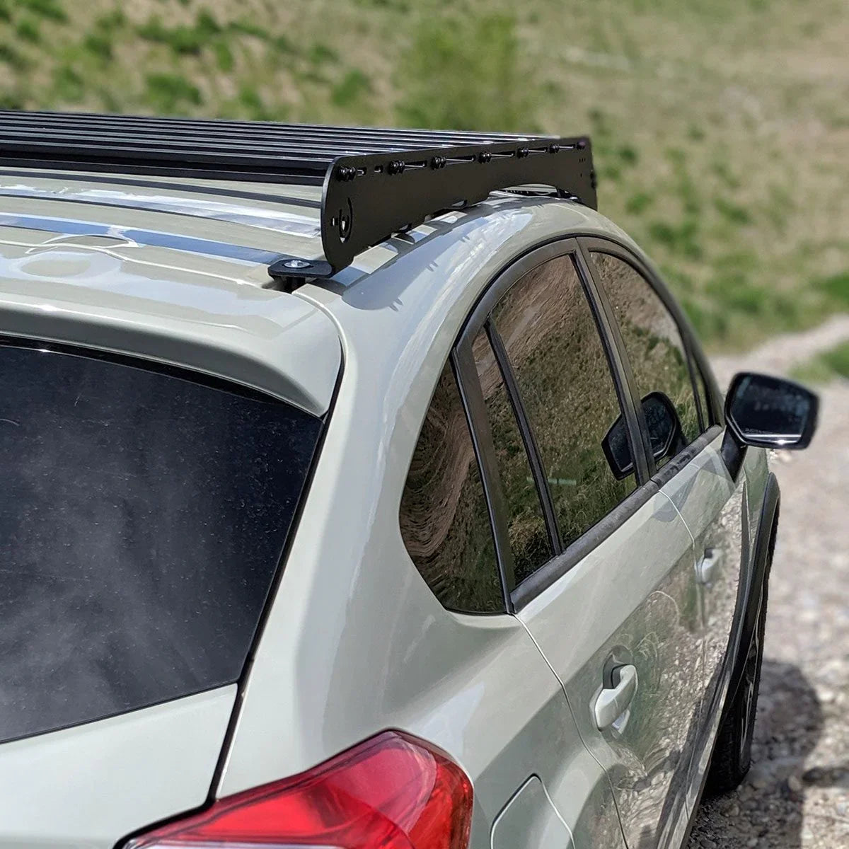 Off-road Subaru Crosstrek with black roof rack on gravel trail