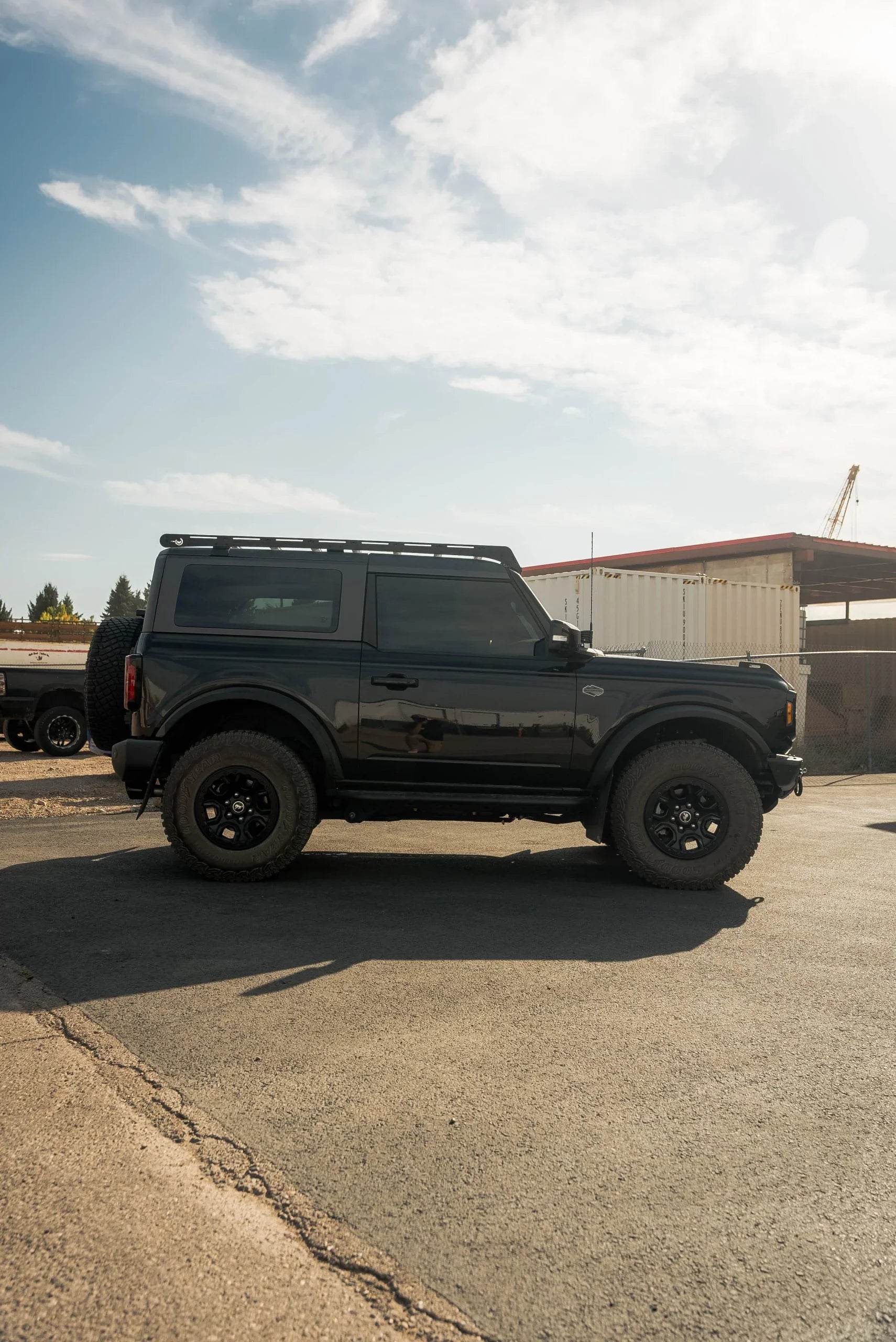 Black 2-door Ford Bronco with roof rack and off-road tires parked outdoors