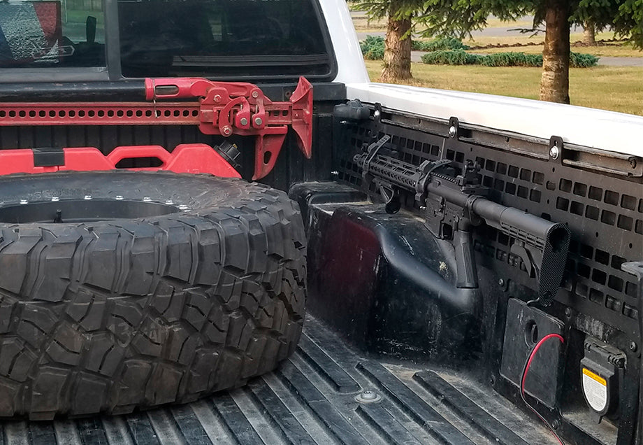 Toyota Tacoma truck bed with MOLLE panel system, off-road tire, and red recovery gear