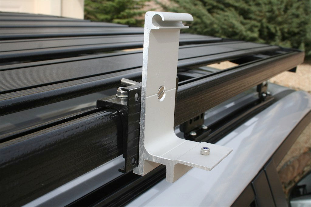 Aluminum roof rack mounting bracket attached to a vehicle crossbar outdoors