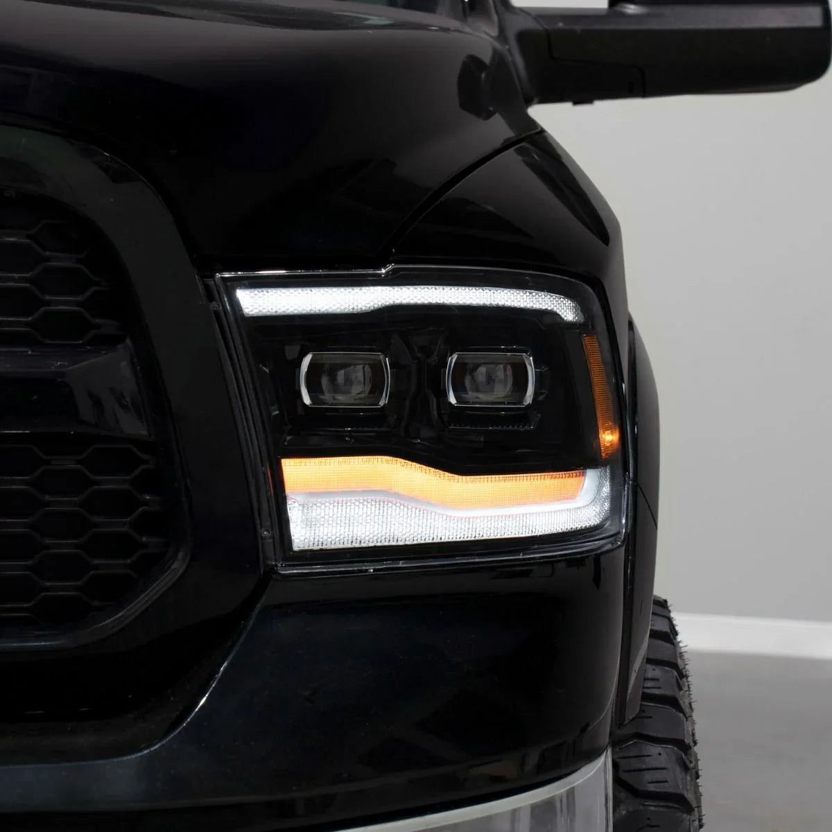 Closeup of 2014 Ram 1500 headlight with LED turn signal illuminated, black truck