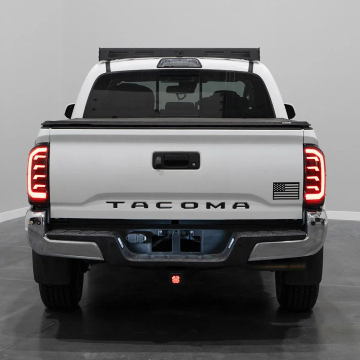Rear view of a white 2018 Toyota Tacoma pickup truck with aftermarket LED tail lights