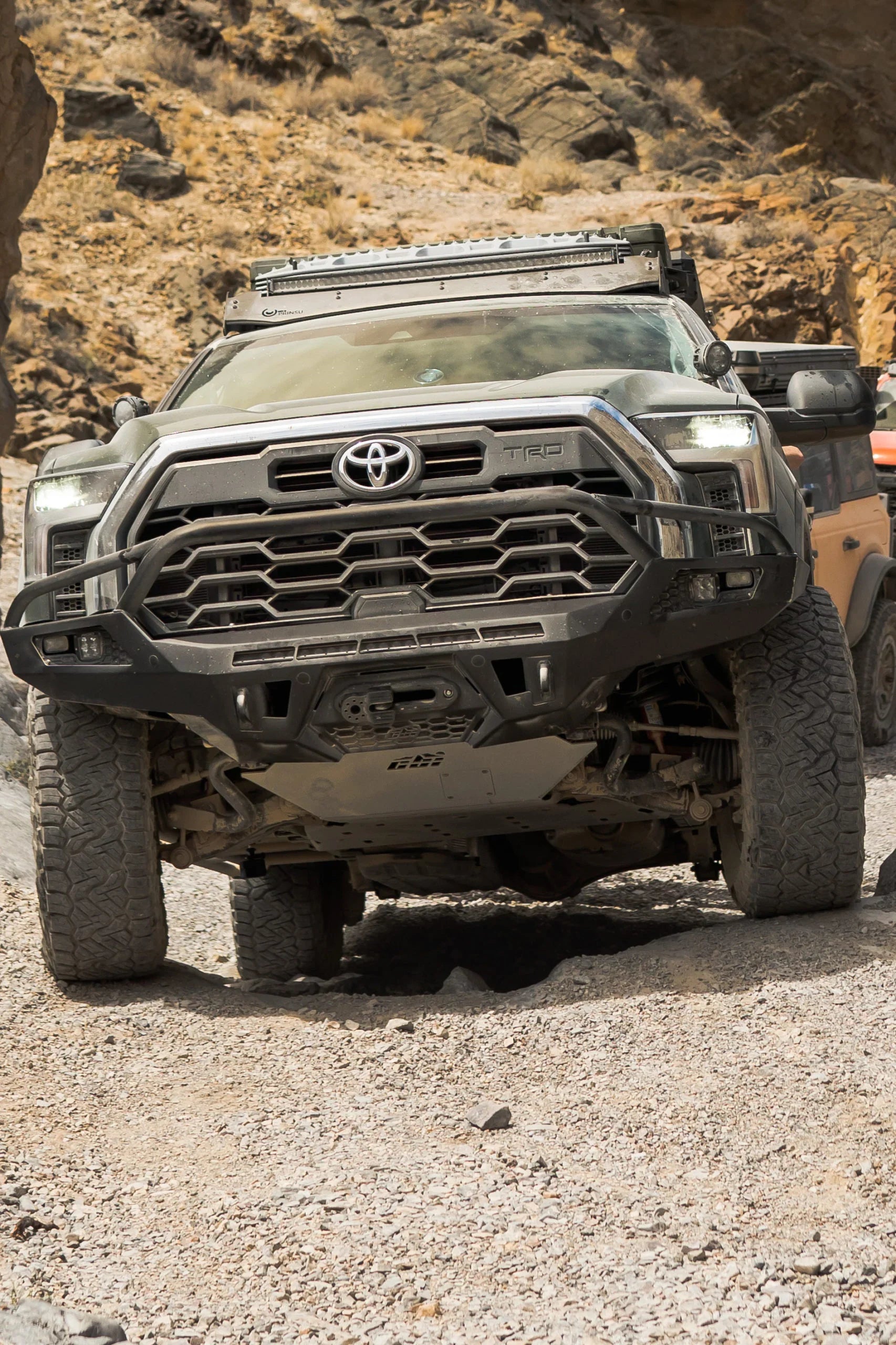 Toyota Tundra with off-road front bumper driving on rocky desert trail